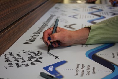 An attendee signs the "What's Booming at Boomerang?" timeline, which reflects the clinic's progress and growth over the past 10 years.