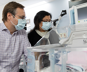 Dr. Cecil Hahn and Dr. Emily Tam look into a crib in the NICU