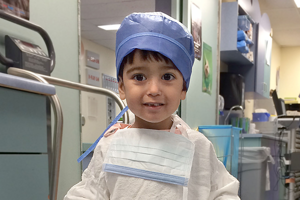 A young boy in a hospital cap and gown.