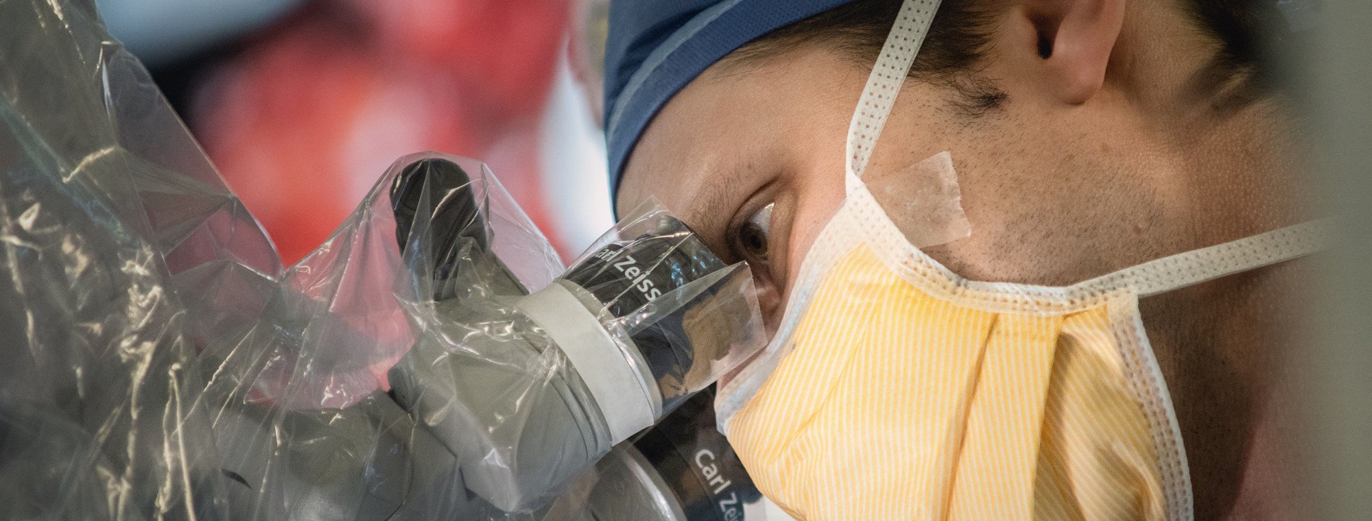 close up of doctor in PPE looking through a microscope device