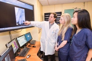 3 dentists are looking at the screen and discussing the case