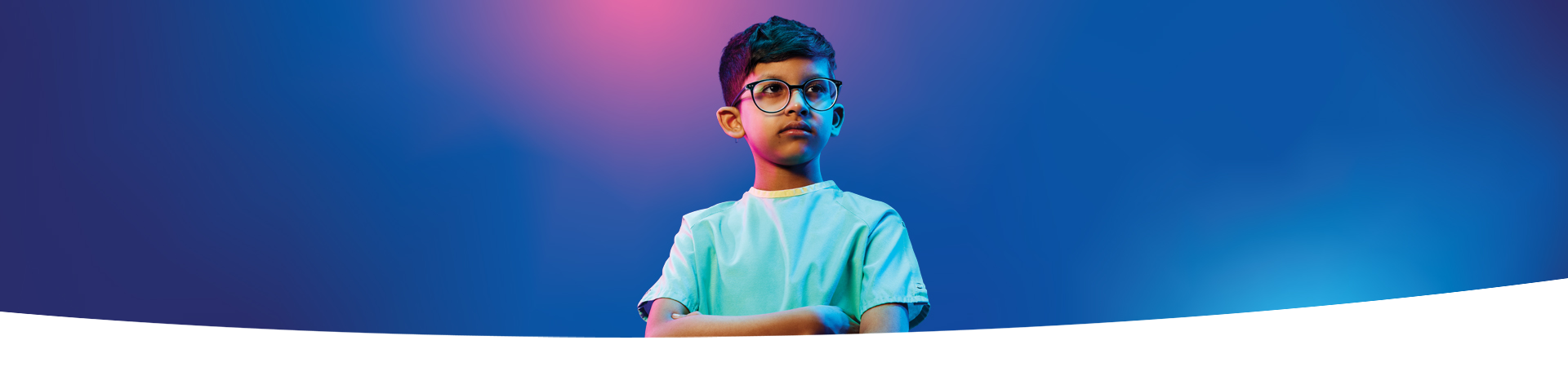 A boy wearing glasses and crossing his arms in front of a blue and pink gradient background.