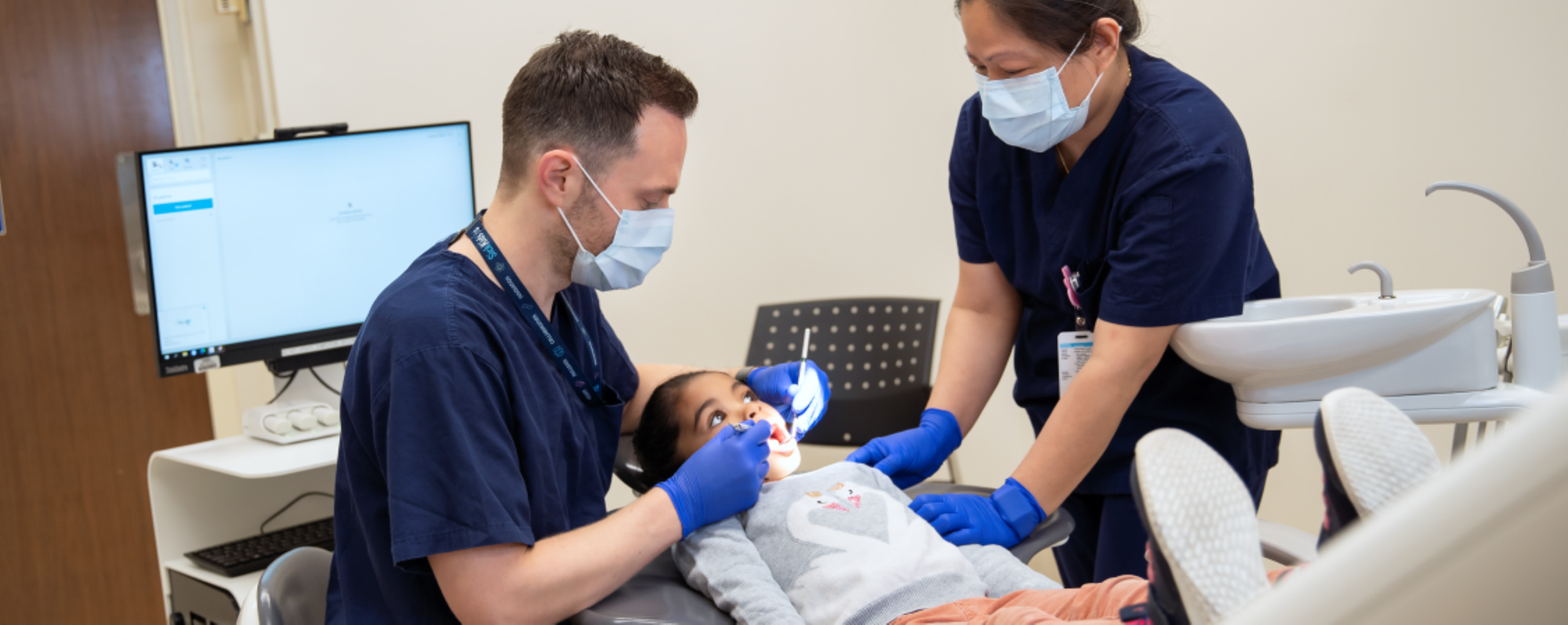 Dentist and dental hygienist examining a child's teeth