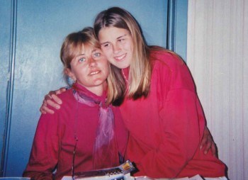 Kristina smiles while hugging her mother, both of them matching in pink sweaters.