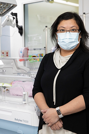 Dr. Emily Tam stands in front of a bed in the neonatal intensive care unit (NICU).