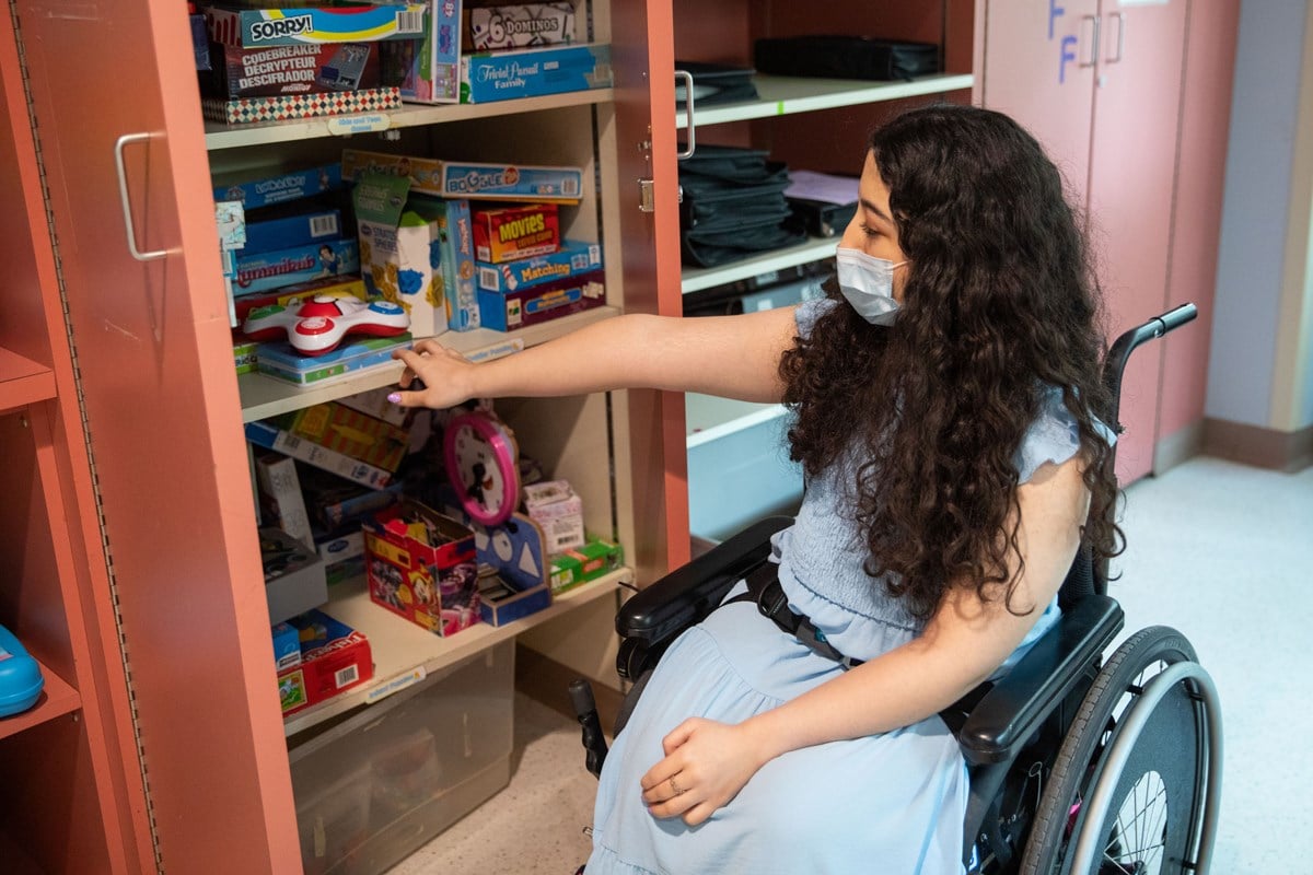 Melika browsing a cupboard full of toys and games.