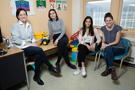A group of four women sit in a bright room in a hospital.