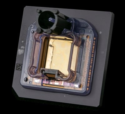 A close up of a square chip with a plastic frame encasing the metal portion of the chip.
