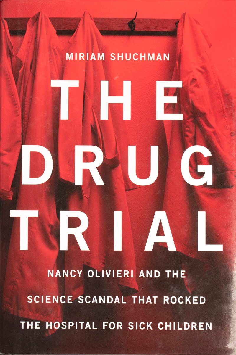 The cover of The Drug Trial. The cover has a red tinted photo of four lab coats hanging on a wall-mounted set of hooks. The sub text reads, "Nancy Olivieri and the science scandal that rocked The Hospital for Sick Children".