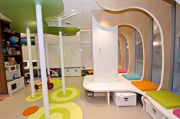 Large view of the room showing kitchen play space, bench seating and pillars.
