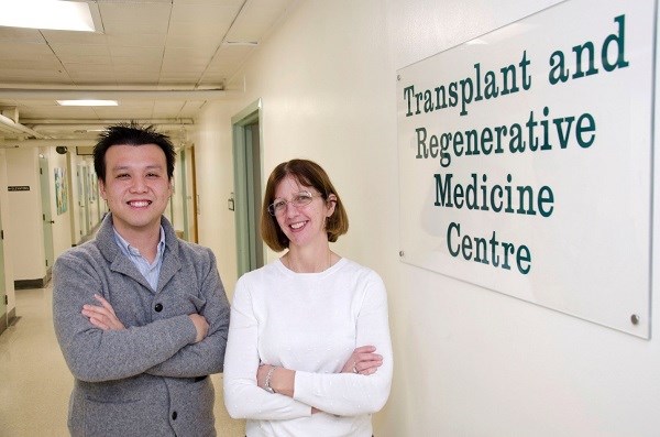 Chia Wei Teoh and Moira Korus stand inside SickKids next to a sign that reads 'Transplant and Regenerative Medicine Centre'