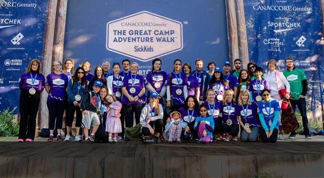 Large group of about 50 people pose together wearing matching purple t-shirts.