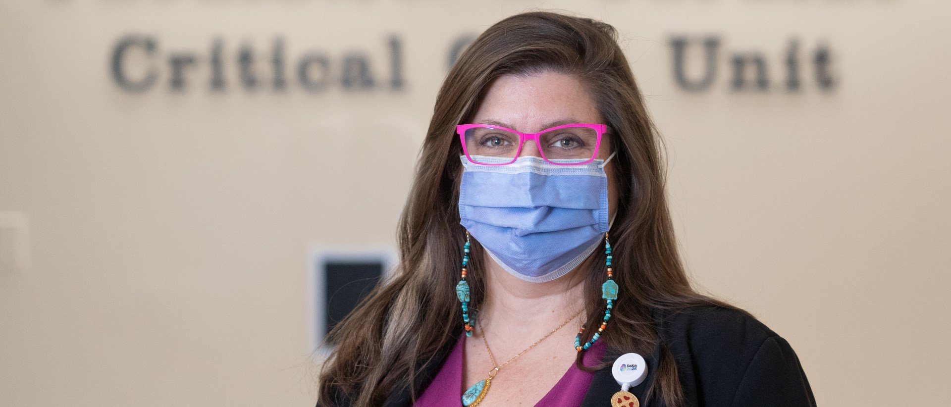 Jackie Hubbert wearing bright pink-framed glasses and a mask.
