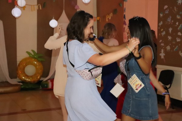 Two girls dance holding hands.