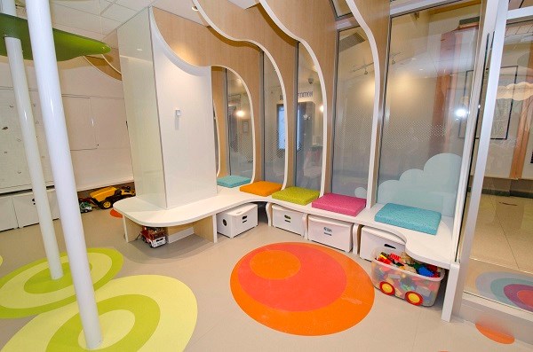 Play area showing bins of toys and a bench seat with colourful circles on the floor.
