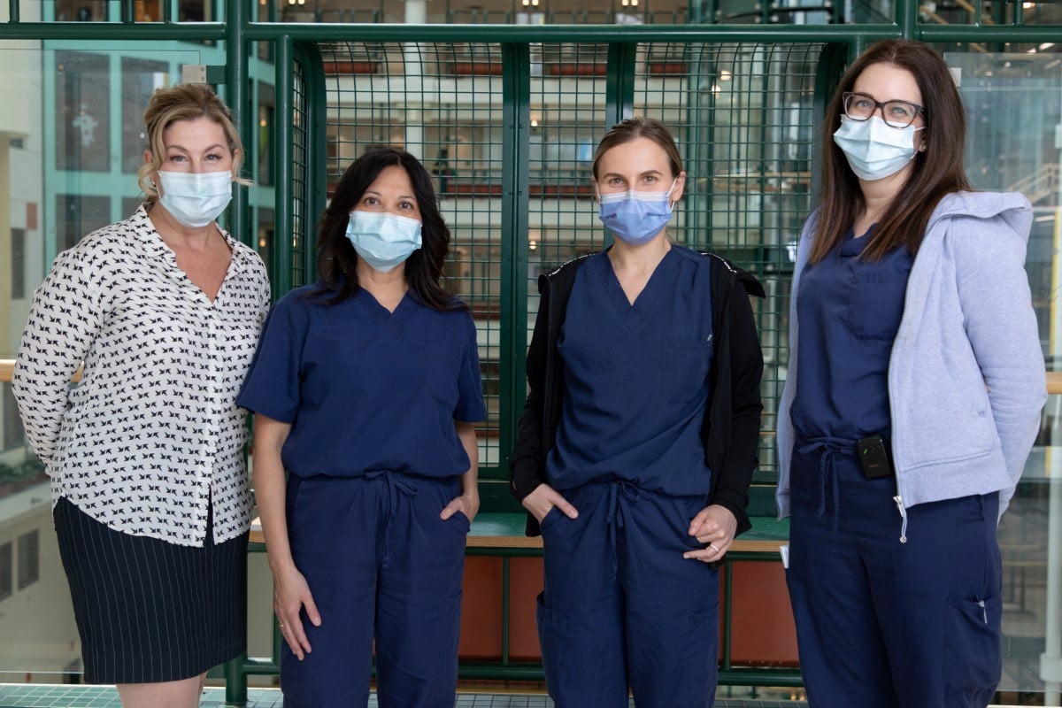 Group photo of Sara Breithard, Arbelle Manicat-Emo, Elizabeth Pawlica and Elisabeth White standing in the Atrium wearing masks.