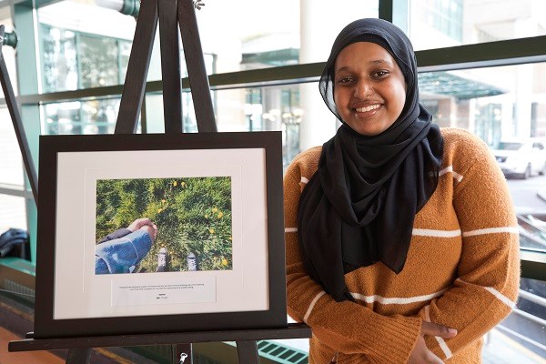 Smiling teen stands next to framed image on an easel.