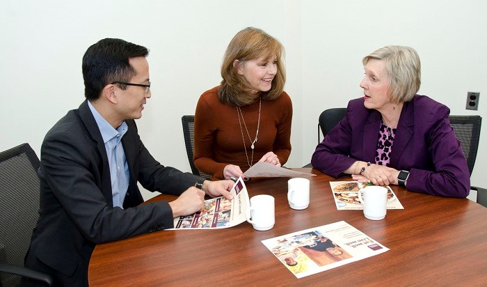 Dr. Lennox Huang, Daina Kalnins and Mary McAllister talk at a table with copies of the new Canada Food Guide
