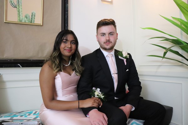 Couple sits on a bench with arms intertwined.