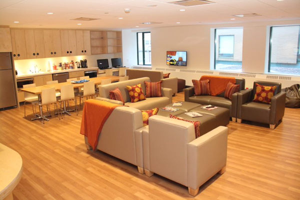 The RMHC Toronto Family Room with hardwood floors, comfy couches, kitchen and dining area.