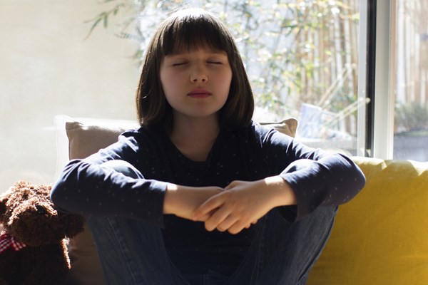 Teen with eyes closed practicing mindfulness while relaxed on a chair