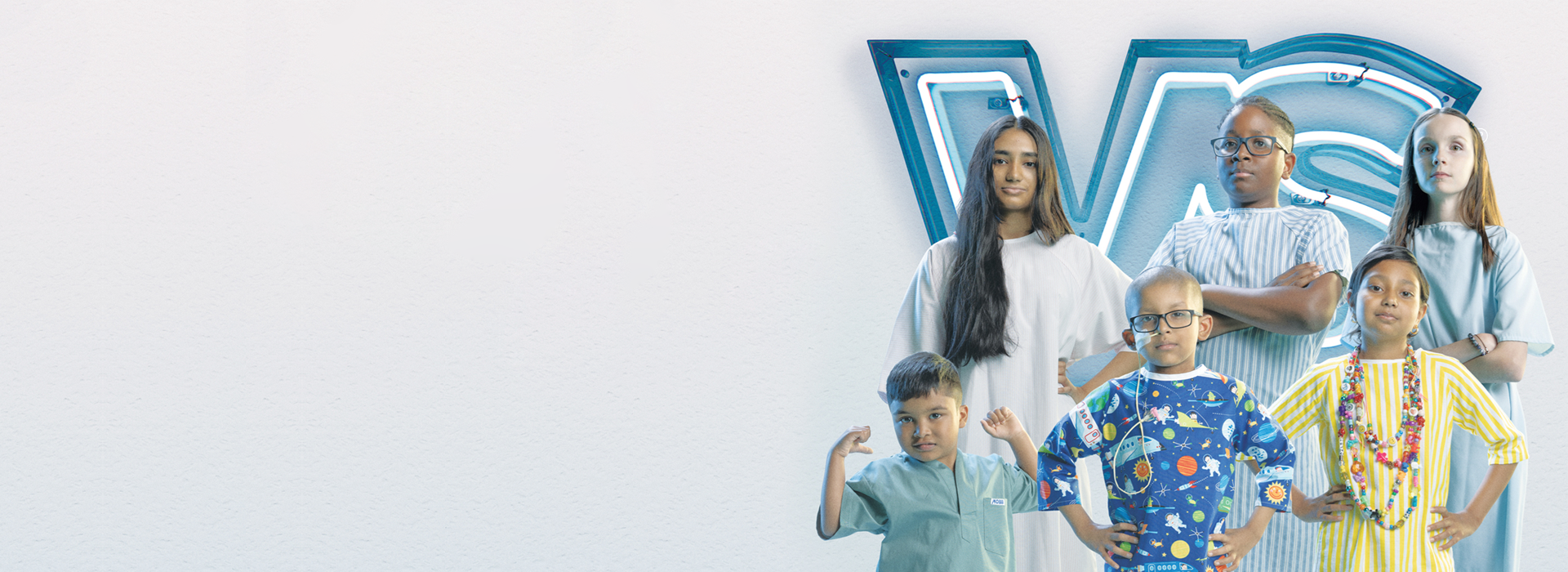 Six children wearing hospital gowns. The children are posing in front of a neon sign with the letters VS. Most of the children pose with their hands on hips or arms crossed. One child poses with arms raised.