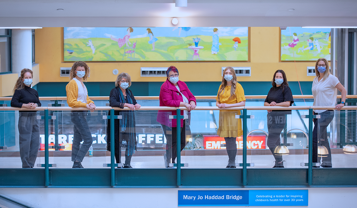 Seven people standing in masks on the Mary Jo Haddad Bridge in the Atrium.