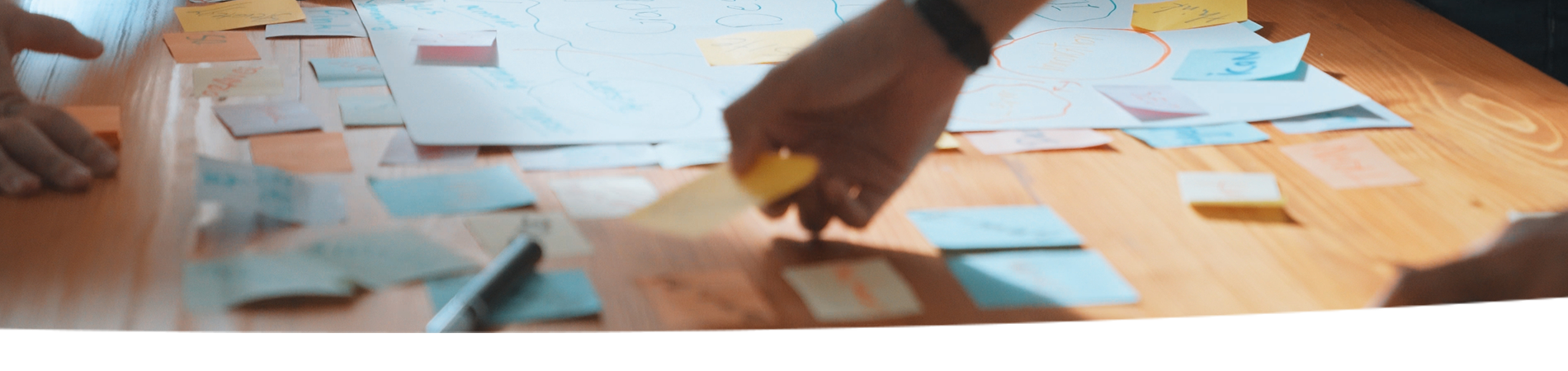 Hands placing sticky notes on a table.
