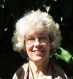 Woman pictured outside in front of greenery.