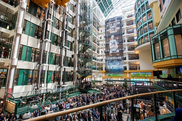 Atrium of hospital filled with people sitting in chairs watching a speaker