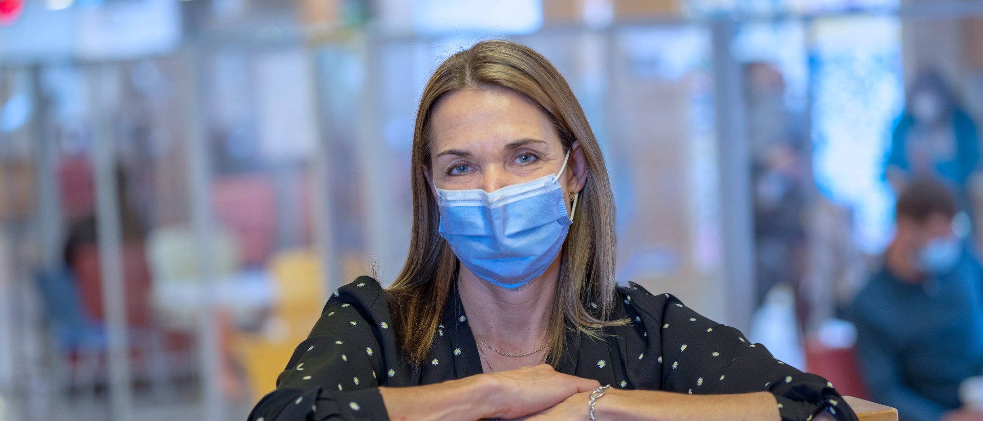 Cory Murphy in a mask. She is facing the camera, while resting her arms on top of a wooden structure.