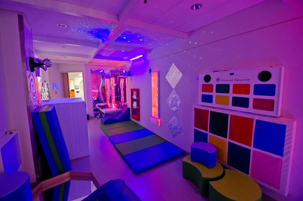 The multisensory room is shown with purple coloured lights and plenty of exciting, interactive play experiences.