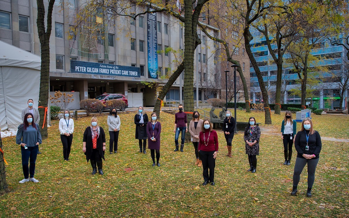 Group of staff stand distanced and masked on a lawn.