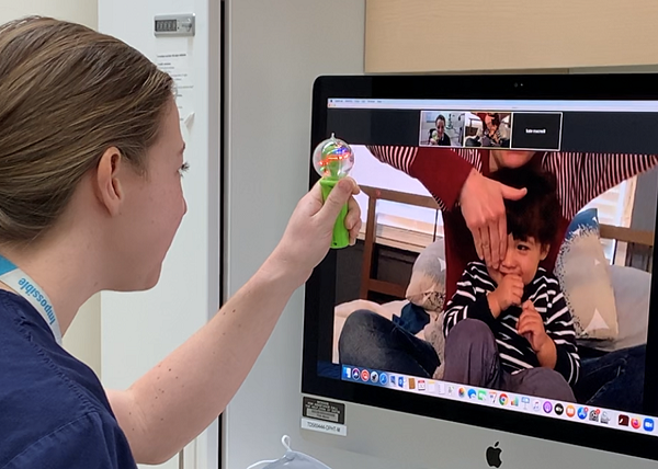 Katelyn MacNeill in front of a screen working with a patient and mom