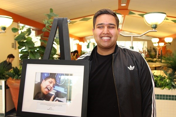 Teen stands next to a framed image he took of himself.