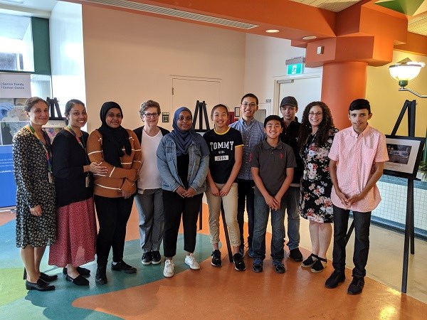 Group of teens and staff pose for a group image in the SickKids cafeteria.