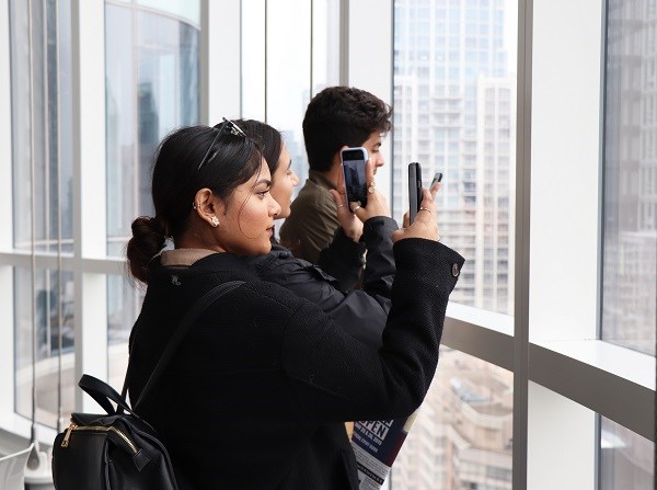 Young woman takes a photo pointing out the window.