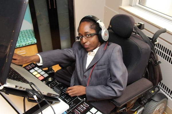 DJ seated behind a desk with music equipment and wearing headphones.