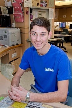 SickKids Volunteer Christian smiling at his desk
