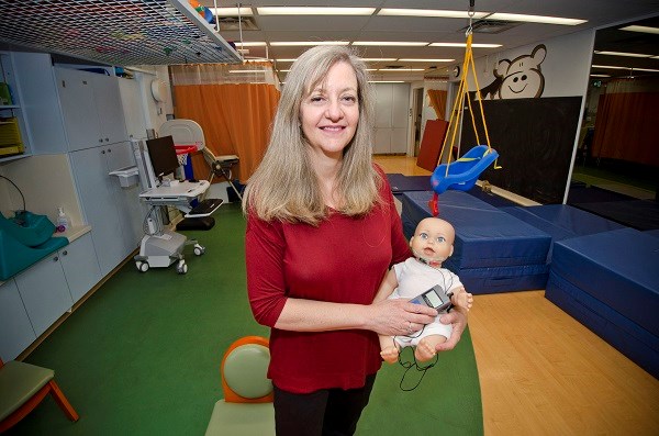 Woman holds infant doll in a therapy room.