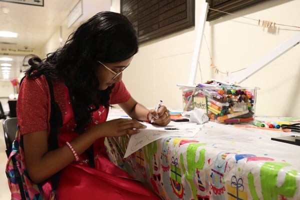 Girl sits at a table using craft supplies.