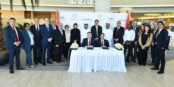 Large delegation of formally dressed staff assemble around a table.