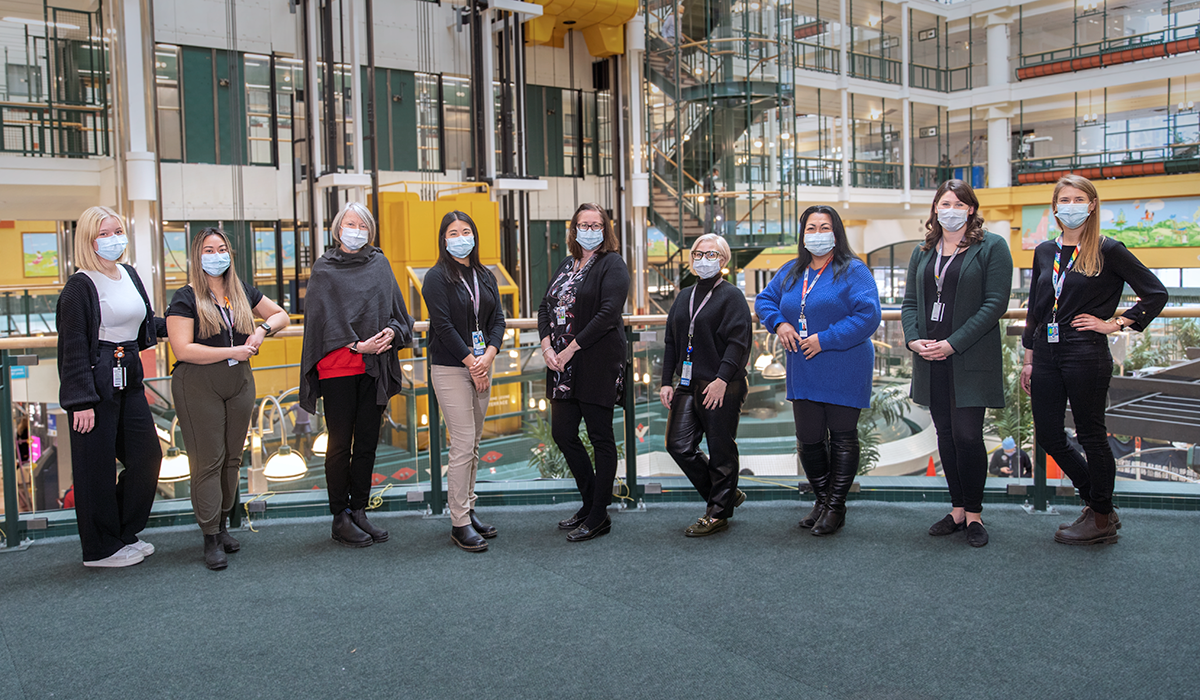 A group of people in masks standing in the Atrium.