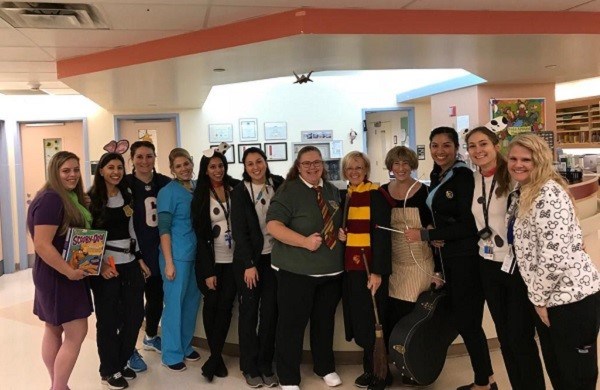 Staff standing together arm-in-arm in a clinical unit, dressed in various costumes.