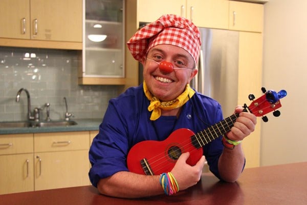 Clown holds a ukulele.