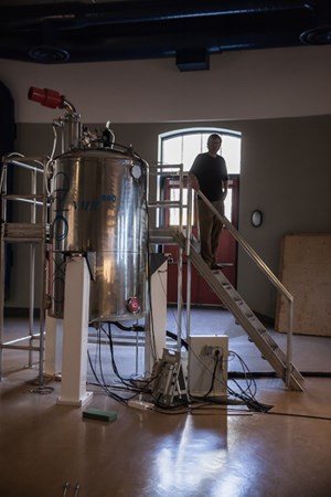 Man stands at the top of a short staircase next to a large machine.