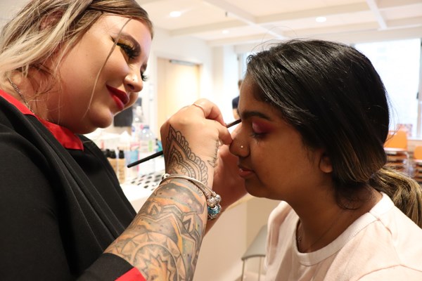 Makeup artist applies makeup to a patient's eyelid.