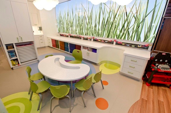 A small table surrounded by chairs, behind a background image of grass with cupboards underneath.
