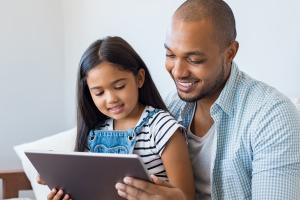 Adult and child use a tablet together.
