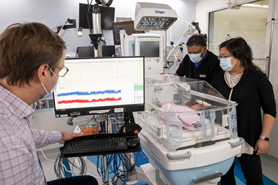 SickKids physicians and EEG technicians gather around an infant in the neonatal intensive care unit to monitor the child’s brain activity.